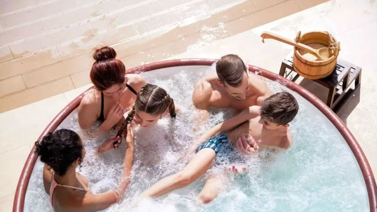 best hot tubs - A man and woman and two children sitting in an inflatable hot tub filled with water