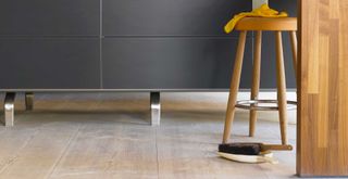 wooden kitchen floor with dustpan and brush to show how often you should sweep and mop your floors