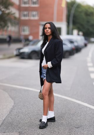 woman wearing white tank top, blazer, and denim shorts