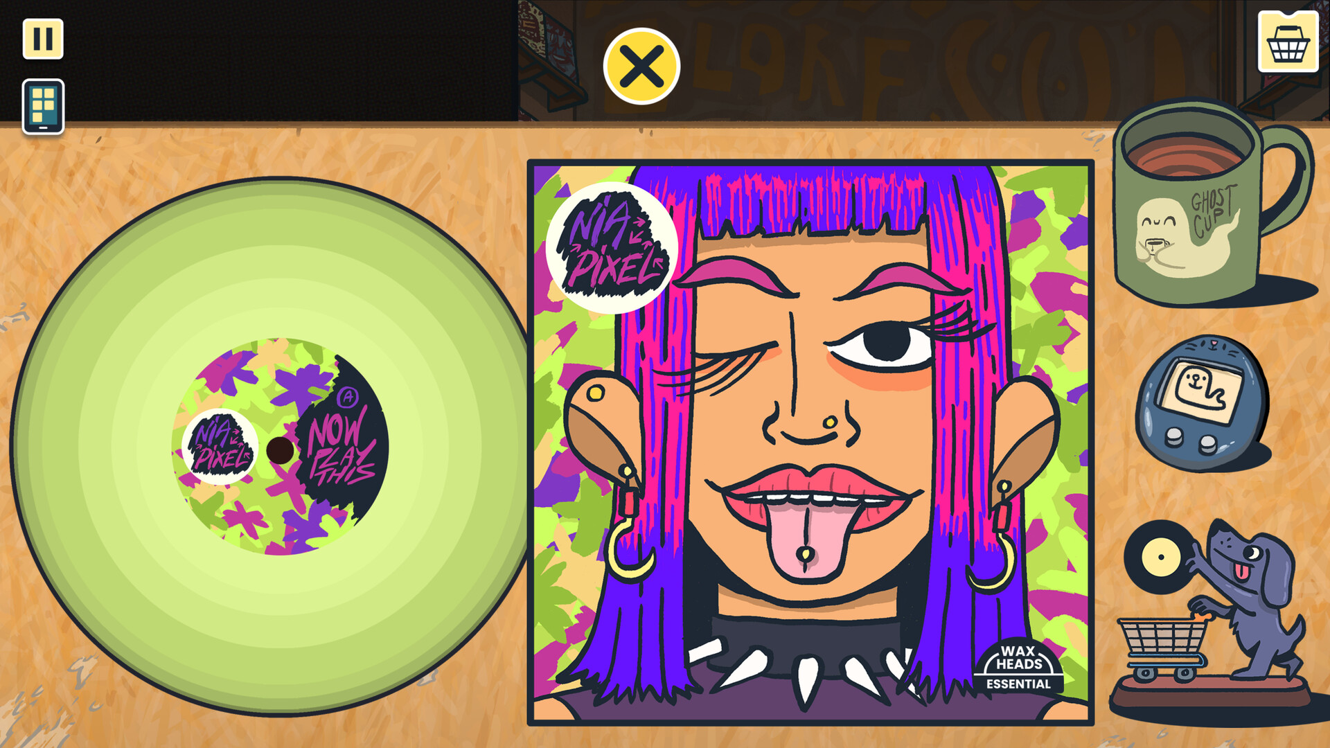 In Wax Heads, a record cover lays on a table next to a mug with a ghost decal on it and a Tamagotchi-like gadget. The record cover is titled Nia Pixel and features woman with purple hair sticking her pierced tongue out and winking.