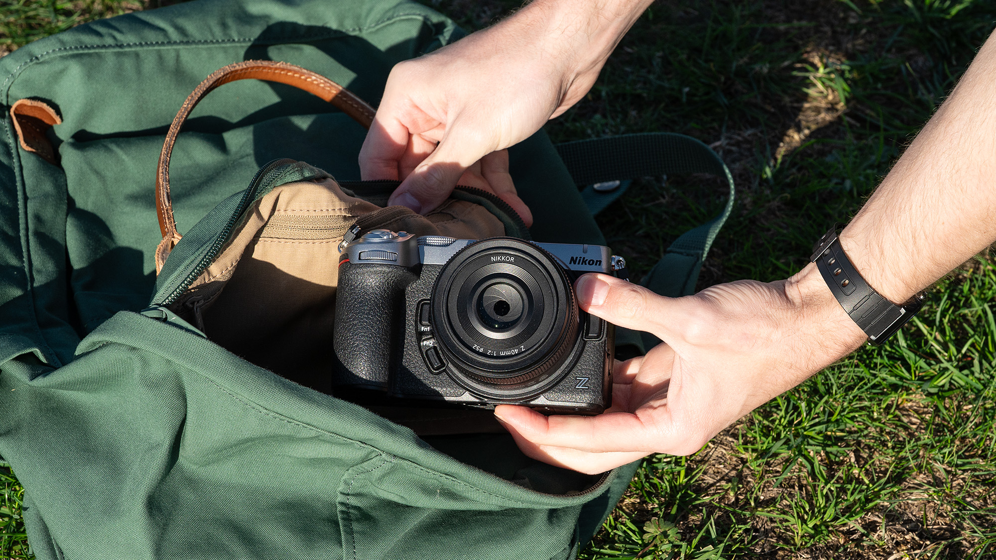 Mike Harris wearing a t-shirt and jeans holding the Nikon Z5IIC on a green background