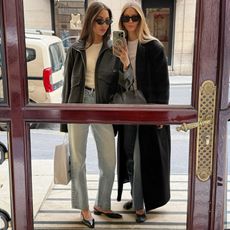 style influencer Felicia Akerstrom and a friend pose for a mirror selfie in Paris wearing black sunglasses, a black jacket and coat, white T-shirts, straight leg jeans and black flats