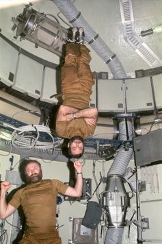 Gerald P. Carr, Skylab 4 mission commander, jokingly demonstrates weight training in zero-gravity, balancing astronaut pilot William R. Pogue upside down on his finger.