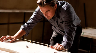 Leonardo DiCaprio as Cobb, looking at his spinning top totem in Inception