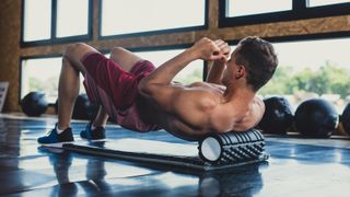 Man rolls out his back muscles using a foam roller
