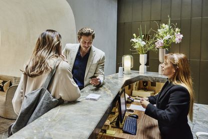 A couple checking in at hotel front desk during business trip 