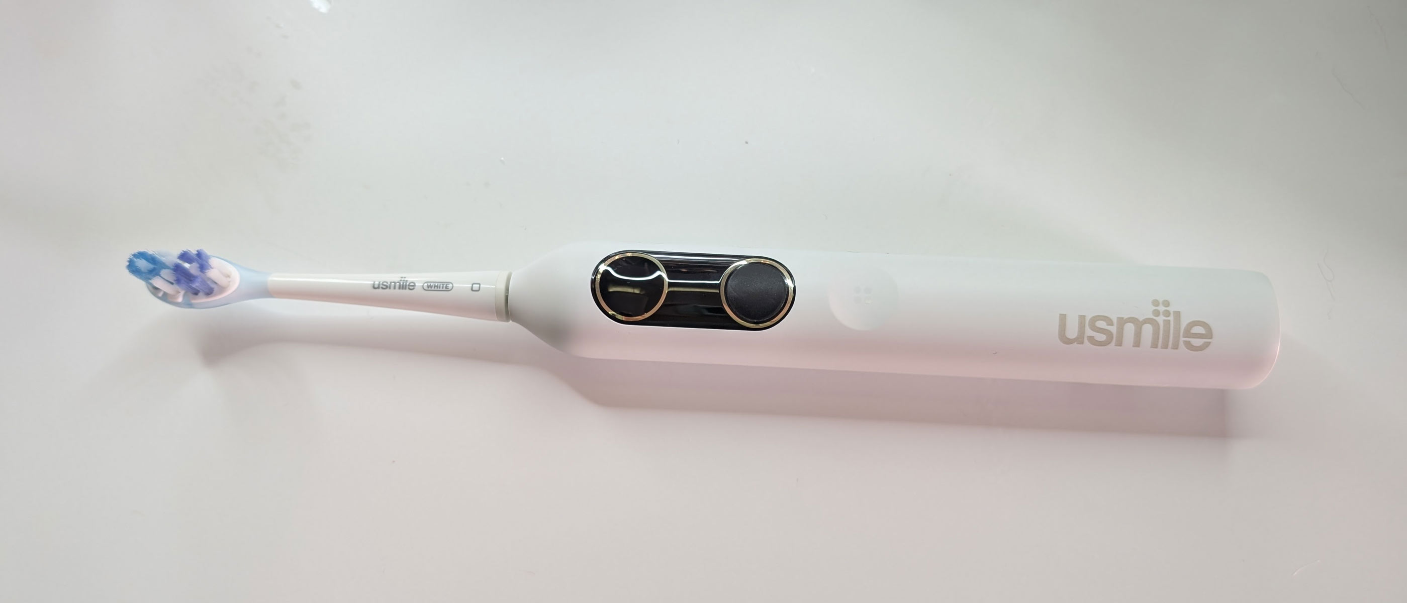 usmile Y10 PRO electric toothbrush laying flat on a white table