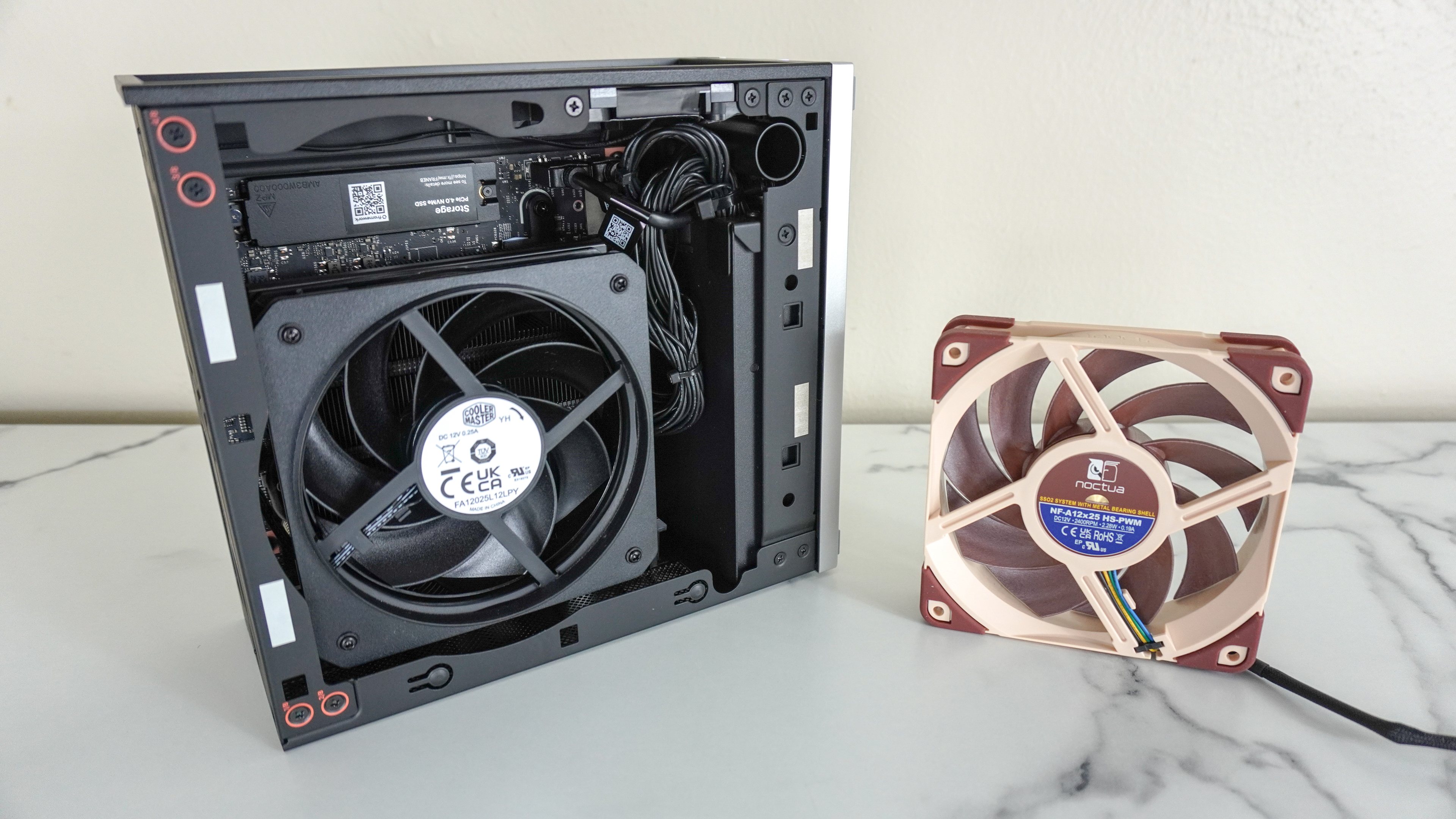 The Framework Desktop open on a desk showing the difference between the Cooler Master and Nocta CPU fan options