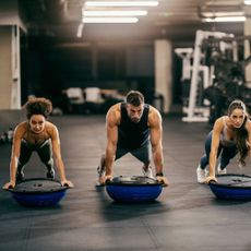 Three people doing bosu ball exercises in the gym