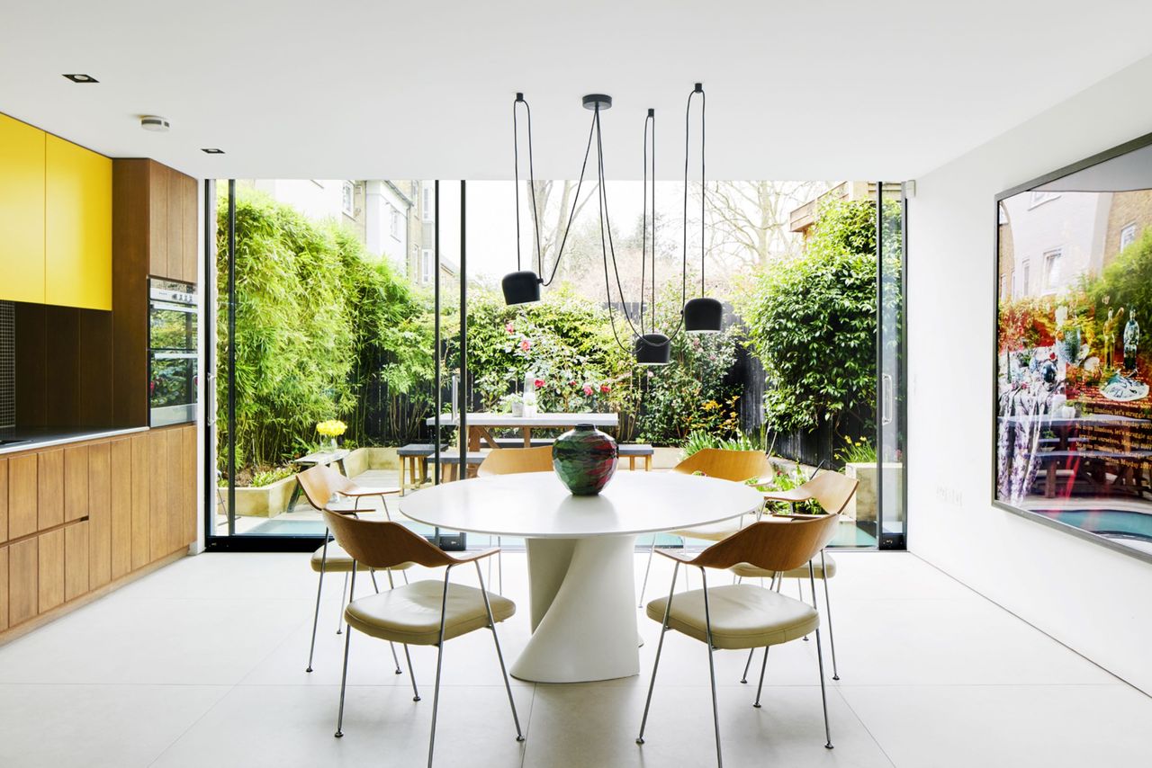 The kitchen-diner looks out onto a full glazed wall onto the tropical garden