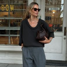 @anoukyve wearing a dark grey deep scoop-neck jumper from Lisa Yang knitwear with grey tailored trousers and brown clutch