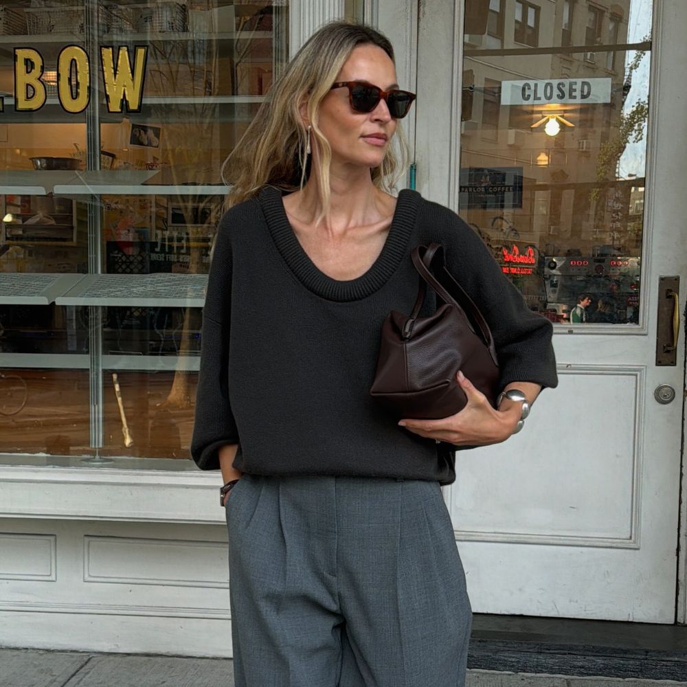 @anoukyve wearing a dark grey deep scoop-neck jumper from Lisa Yang knitwear with grey tailored trousers and brown clutch