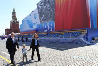 Expedition 36/37 Flight Engineer Karen Nyberg (right) takes a stroll through Red Square in Moscow in front of a grandstand and the Kremlin May 8, 2013 with her husband, astronaut Doug Hurley (left) and their 3-year-old son Jack.
