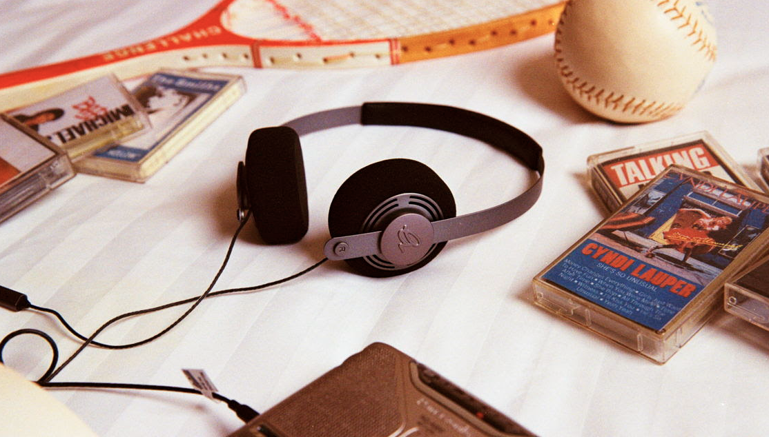 Gadhouse Wesley headphones on the head of a boy and also on a bed surrounded by cassette tapes