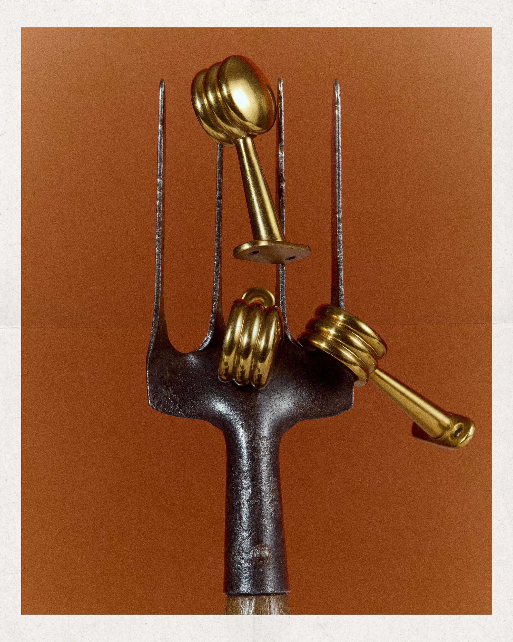 Image of three kitchen rail stops on a brass garden tool in front of a burnt orange background.