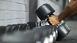 What is blood flow restriction training: Image shows person picking up dumbbells
