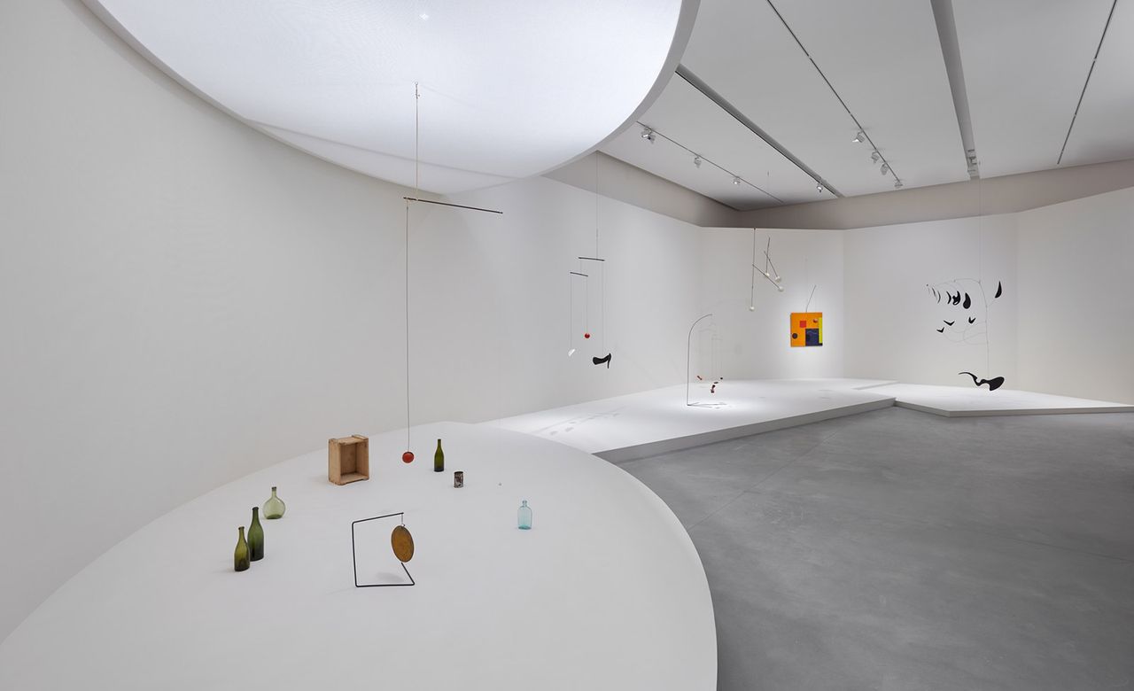 Inside view of the gallery, with different installations shown. The gallery is all white, with a gray floor.