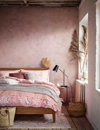 bedroom with pink plaster effect wall and floral bedspread