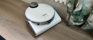 white robot vacuum being tested on hard wood floors