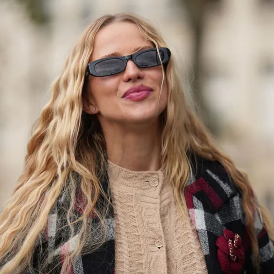 affordable hair dryers Woman with long blonde, wavy hair walks down the road during fashion week in a tartan jacke t