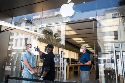 A security guard takes the temperature of a customer outside the Apple Store on May 13, 2020 in Charleston, South Carolina