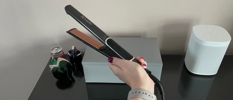 The Revlon Pro Collection Salon Straight Copper Smooth Extra Long Styler being held in a hand