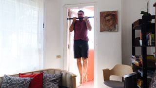 Man using telescopic pull-up bar at home