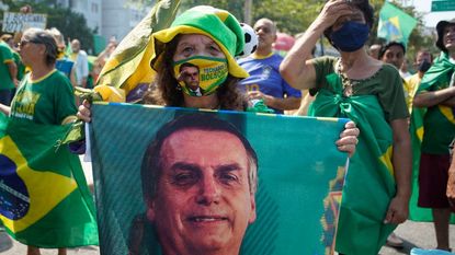 A supporter of Jair Bolsonaro wears a mask with his photo on it.