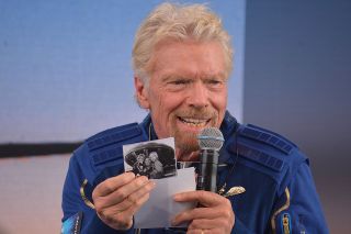 Virgin Galactic founder Richard Branson holds up a photo of him with his children that he flew to space inside his flight suit pocket aboard the Unity 22 suborbital mission flown from Spaceport America in New Mexico on July 11, 2021.