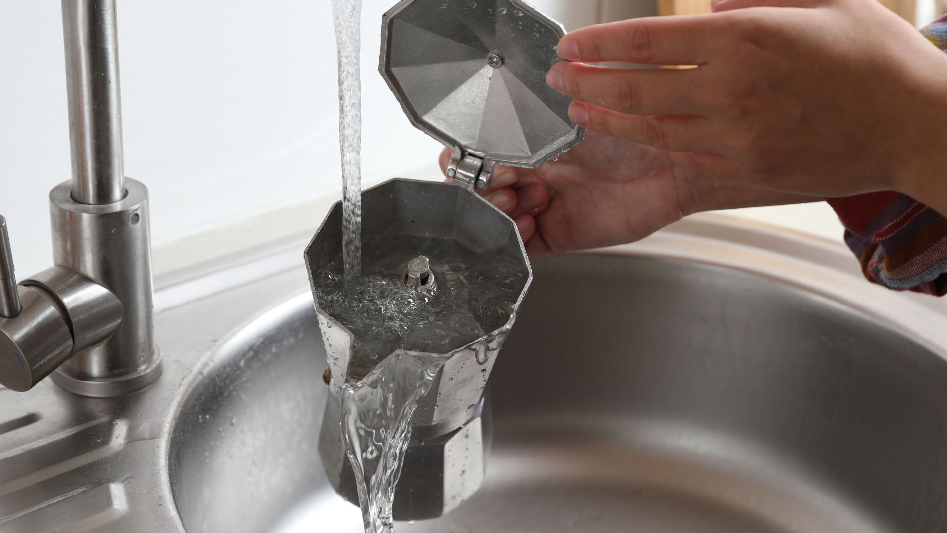 picture of woman rinsing out an empty moka pot under the tap