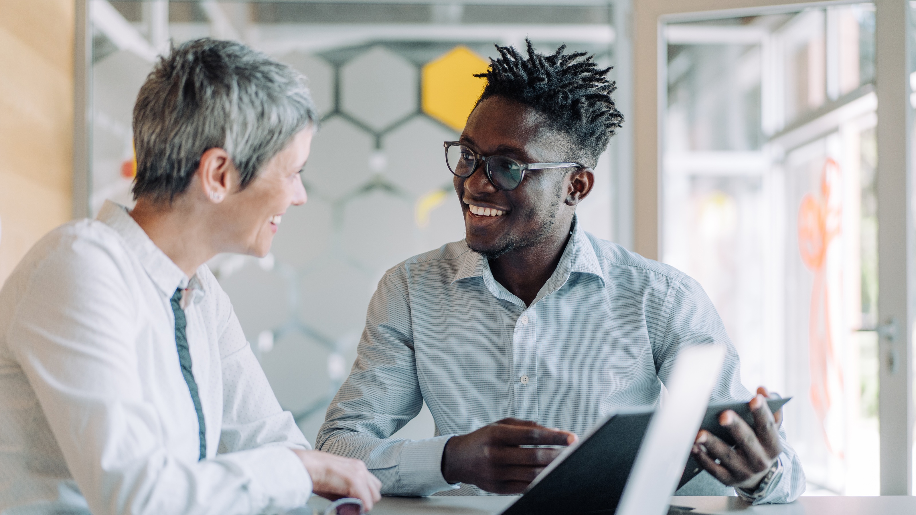 A financial adviser talks with his older client in an office. 