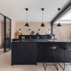 Black kitchen counter and chairs with pale pink wall 