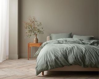 Coyuchi Organic Crinkled Percale™ Sheet Set in sage on bed in front of beige wall with wooden nighttand