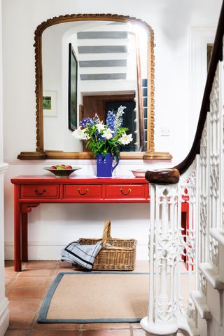 staircase hallway with red console table