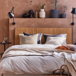 Terracotta walls with shelf over neutral colored bed