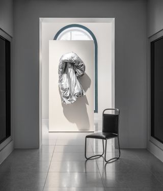 Contemporary art featuring a duvet-style feature on display with a black chair in the foreground.