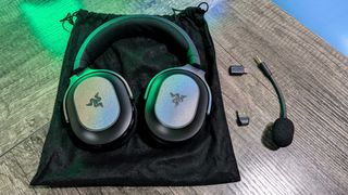 A Razer Barracuda X Chroma headset on its included travel bag, with its in-box accessories next to it.