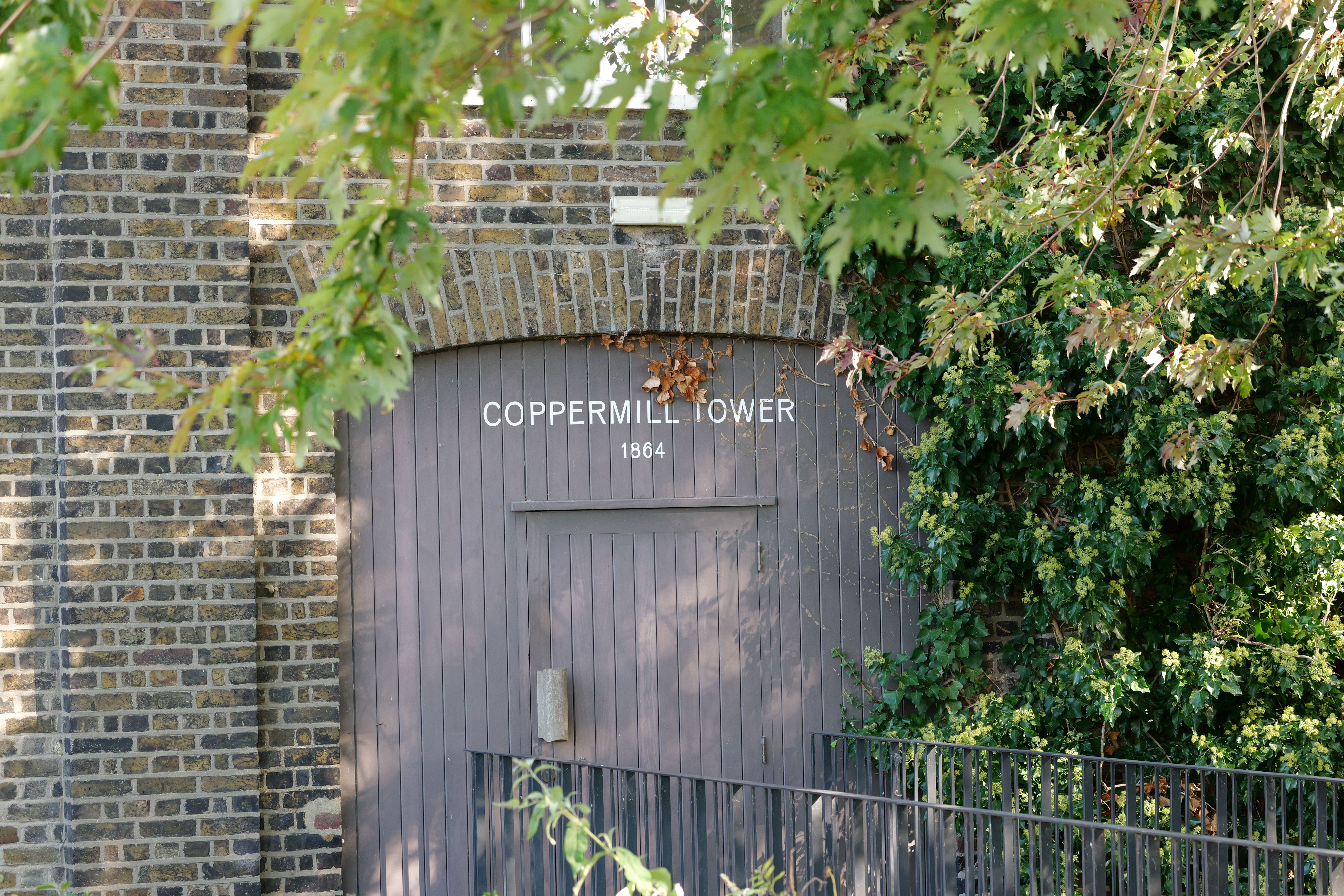 The door to a pump house with a copper mill tower 1864 printed on it