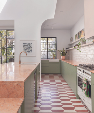 modern kitchen with light green and beige marble countertop cabinetry and patterned orange and white tiled floor