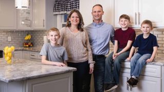 The Krall family, including the parents and three young boys, pose for a photo in their family kitchen.