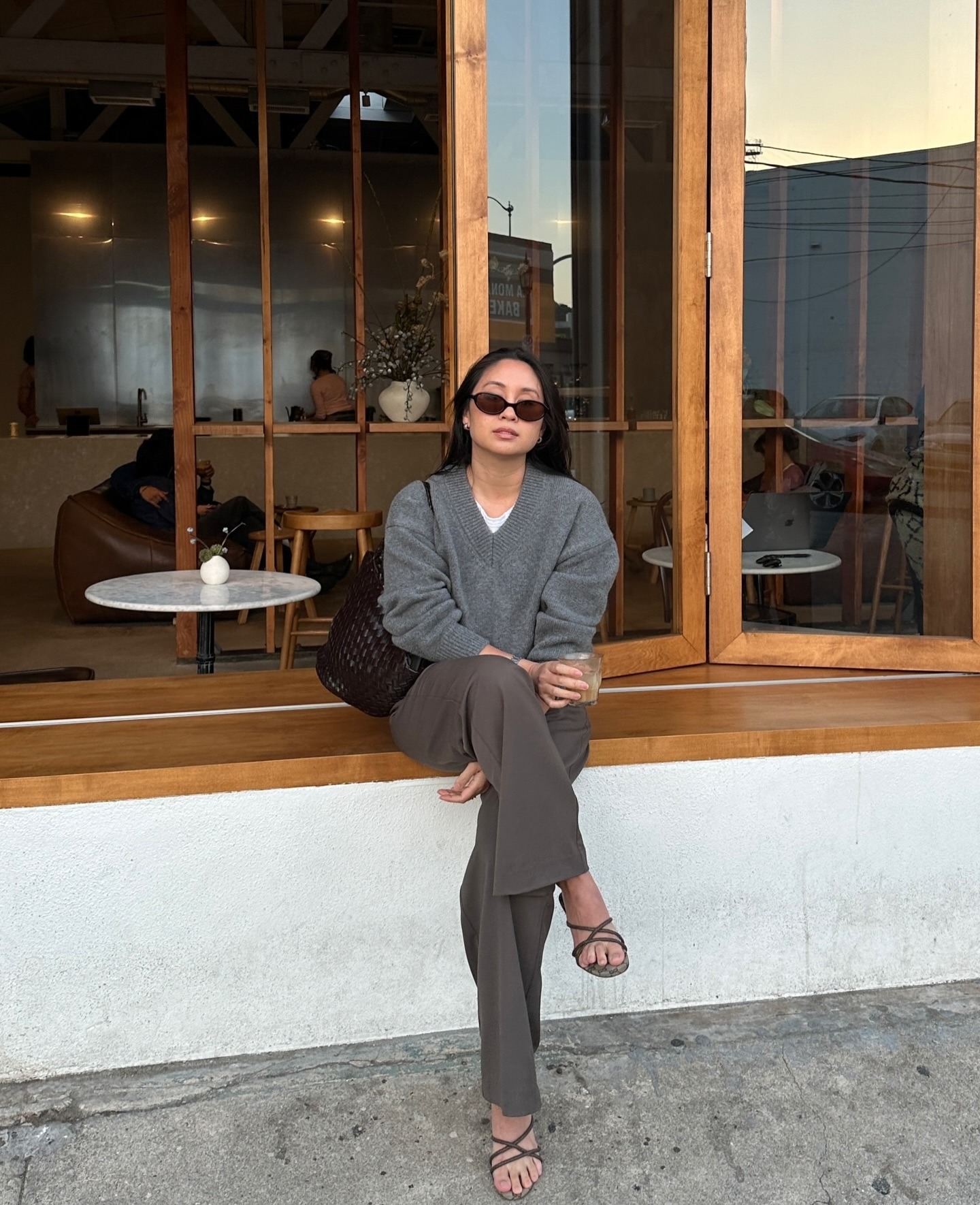 Woman in a gray V-neck sweater and pants.