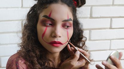 Woman Putting On Evil Clown Makeup for Halloween