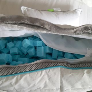 A pillow unzipped to show blue foam cubes inside