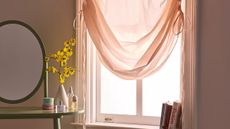 Urban Outfitters tie up sheer curtains hanging over a light-flooded bedroom window