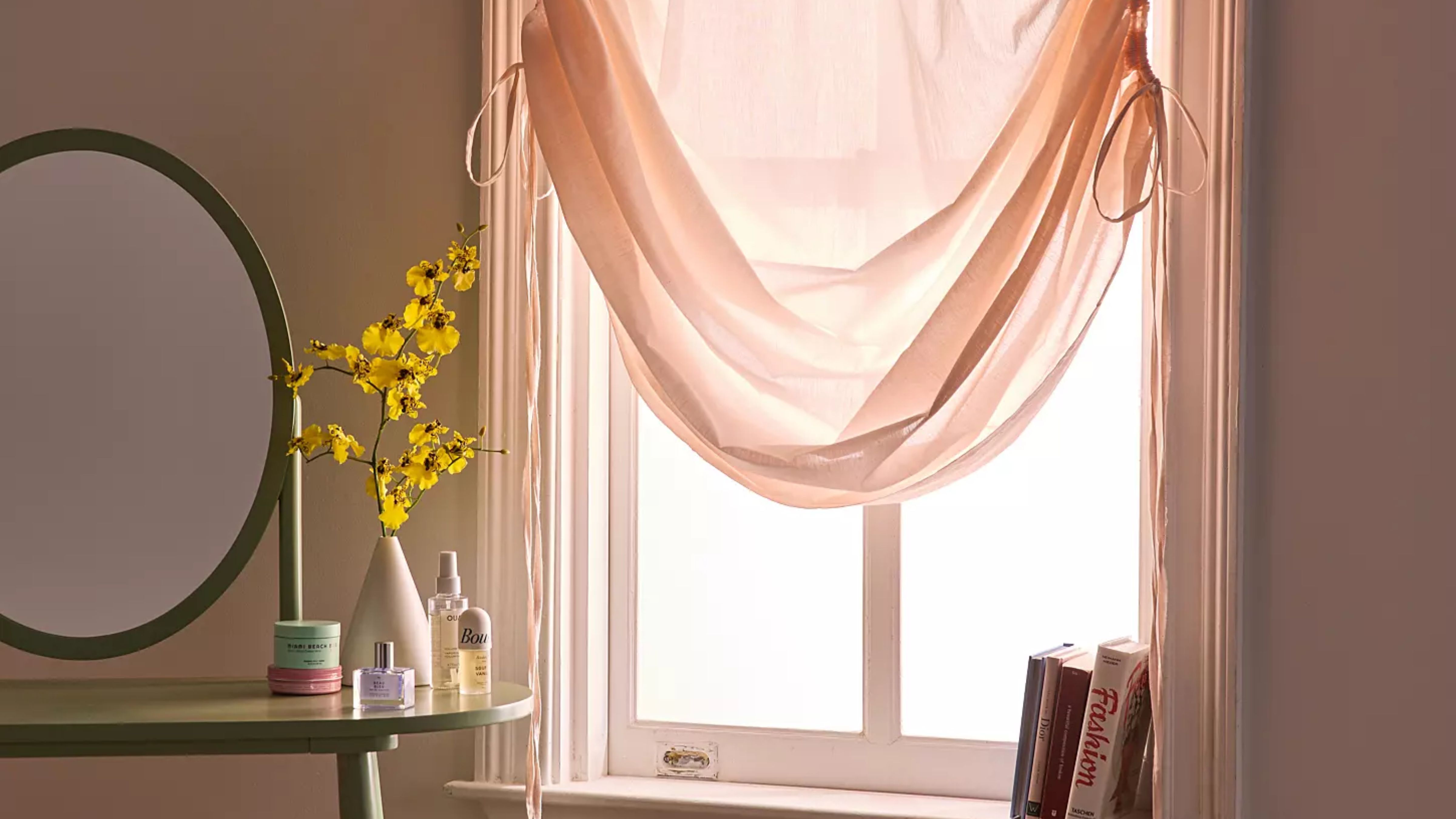 Urban Outfitters tie up sheer curtains hanging over a light-flooded bedroom window 
