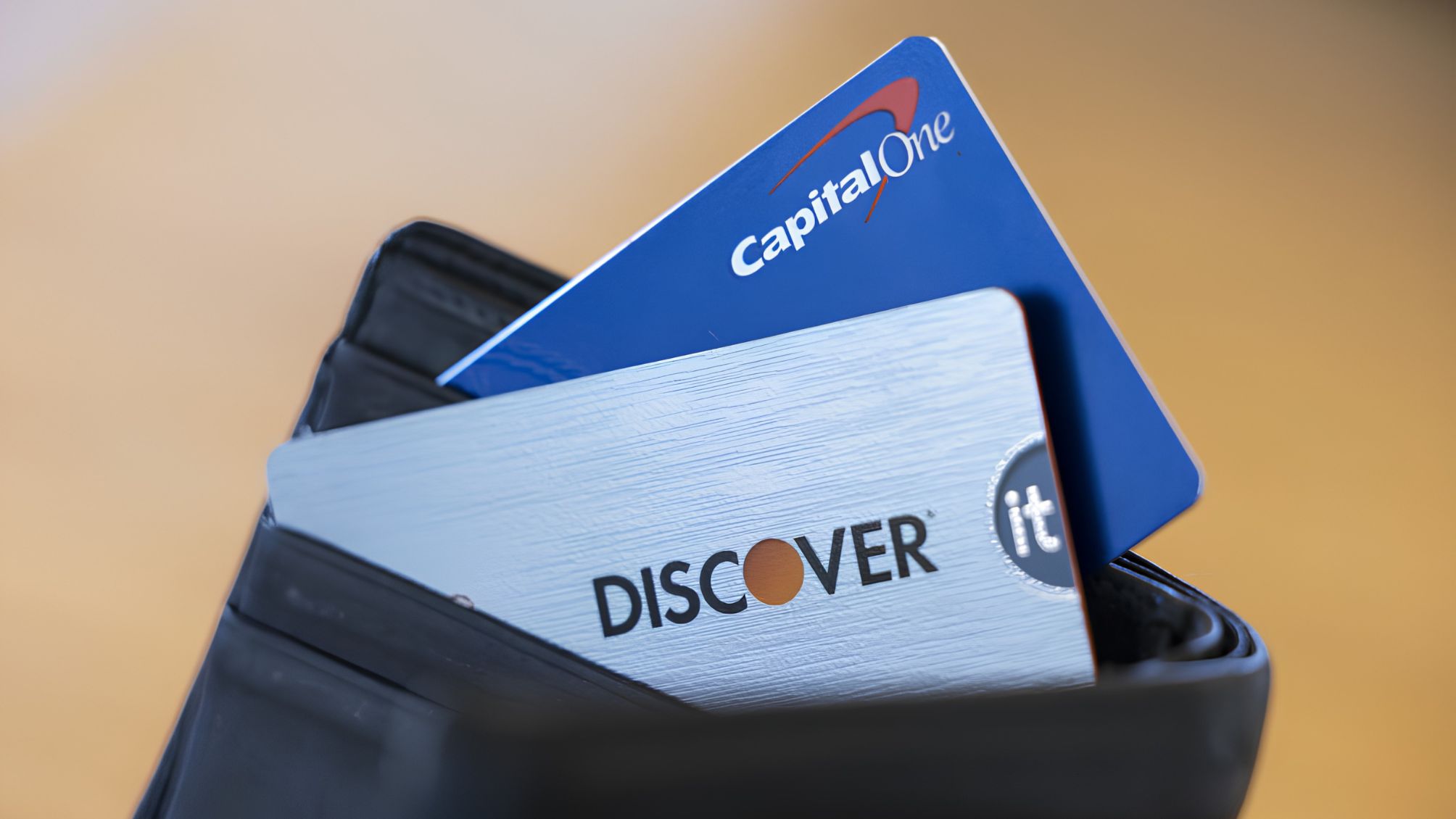 A wallet with a Discover and Capital One credit card sticking out 