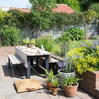 country cottage garden dining table and benches with planting and lavender and a floor cushion