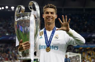 Cristiano Ronaldo celebrates with the Champions League trophy after Real Madrid's win over Liverpool in the 2018 final and holds up five fingers to represent his five wins in the competition.