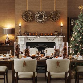 Neutral dining room with fireplace and table and chairs, Christmas decorations and wreaths on the wall