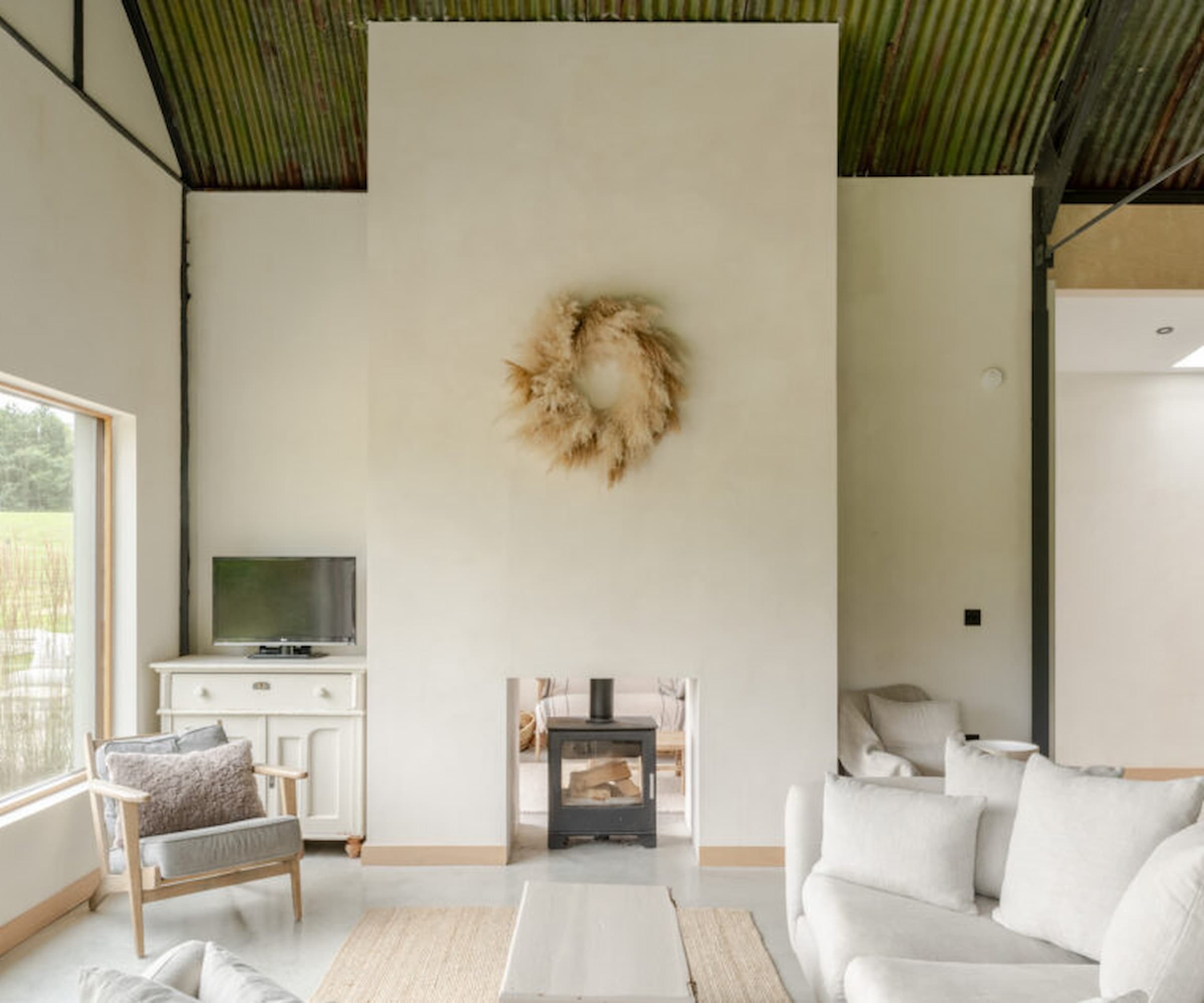 A living area with a central stove separating it from the kitchen